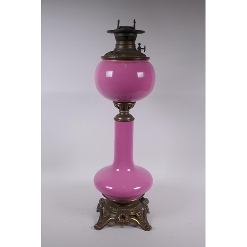 154 - A pink glass and brassed metal oil lamp converted to electricity, 64cm high