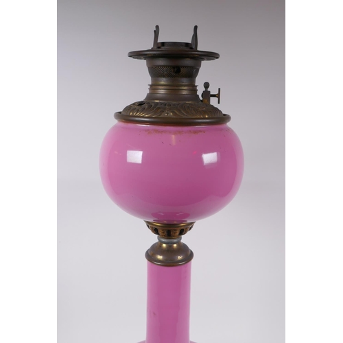 154 - A pink glass and brassed metal oil lamp converted to electricity, 64cm high