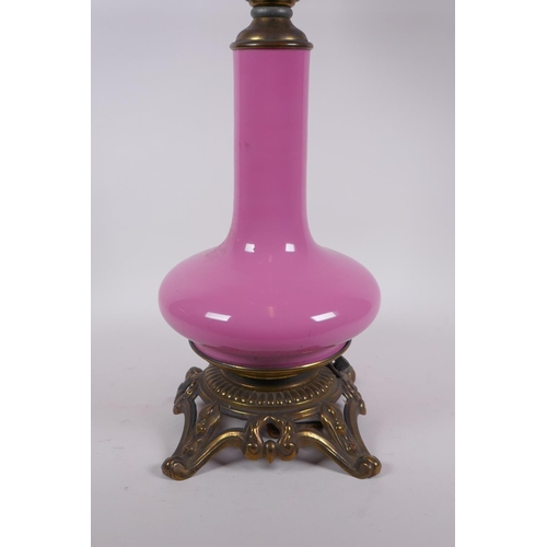 154 - A pink glass and brassed metal oil lamp converted to electricity, 64cm high