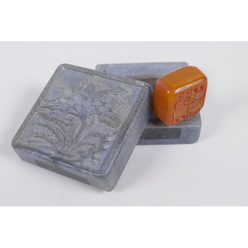 155 - A Chinese hardstone box with carved lotus flower decoration to the cover, containing an amber soapst... 