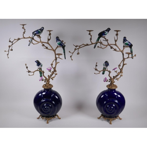 20 - A pair of polychrome porcelain and gilt metal pricket candlesticks decorated with song birds perched... 