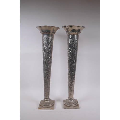 207 - A pair of continental white metal trumpet shaped vases with repousse vine decoration and frilled rim... 