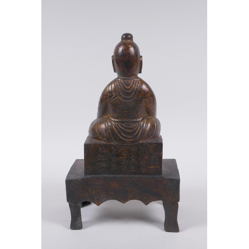 213 - A Chinese gilt bronze figure of Buddha seated on a throne, inscription verso, 26cm high