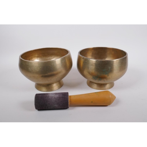 275 - A pair of Tibetan polished bronze footed singing bowls, with wood hammer, 12cm high x 19cm diameter