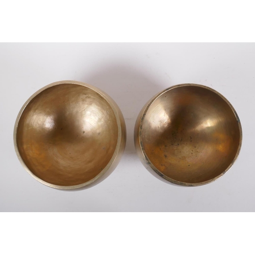 275 - A pair of Tibetan polished bronze footed singing bowls, with wood hammer, 12cm high x 19cm diameter