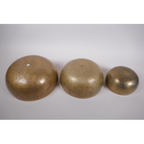 276 - Three Tibetan graduated polished bronze singing bowls, with hammered finish and two wood hammers, la... 