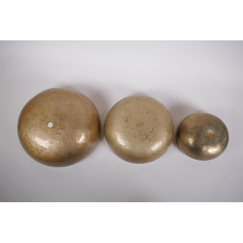 276 - Three Tibetan graduated polished bronze singing bowls, with hammered finish and two wood hammers, la... 