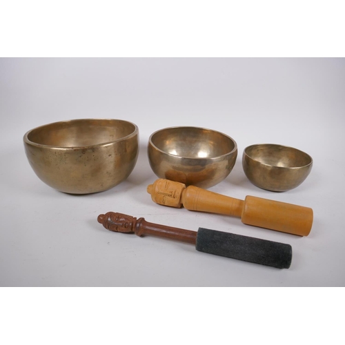 277 - Three Tibetan graduated polished bronze singing bowls with hammered finish, and two wood hammers, la... 