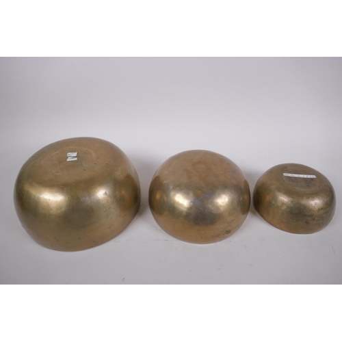 277 - Three Tibetan graduated polished bronze singing bowls with hammered finish, and two wood hammers, la... 