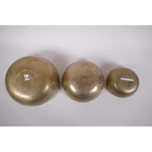 277 - Three Tibetan graduated polished bronze singing bowls with hammered finish, and two wood hammers, la... 