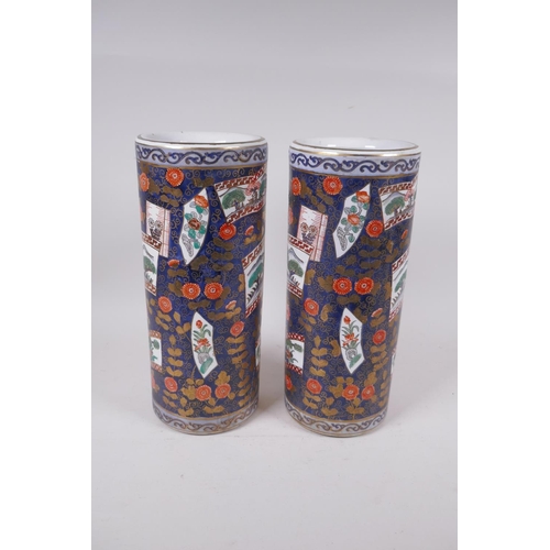 298 - A pair of Japanese blue ground porcelain cylinder vases with decorative panels depicting landscape s... 