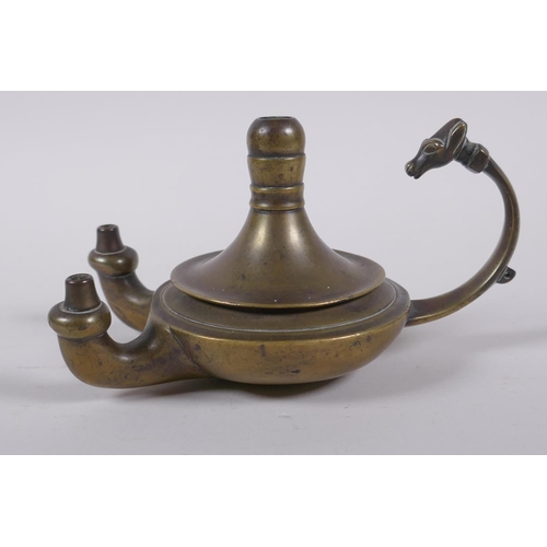 37 - An antique brass twin spout whale oil lamp with animal mask decoration to handle, 15cm long