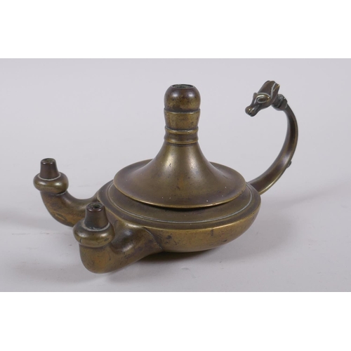 37 - An antique brass twin spout whale oil lamp with animal mask decoration to handle, 15cm long