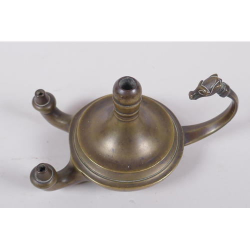 37 - An antique brass twin spout whale oil lamp with animal mask decoration to handle, 15cm long