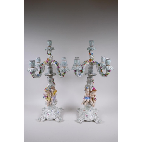 52 - A pair of continental porcelain four branch candelabra decorated with putti, 59cm high