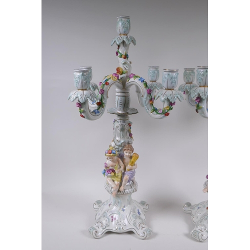 52 - A pair of continental porcelain four branch candelabra decorated with putti, 59cm high