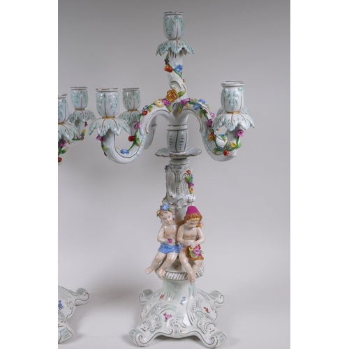 52 - A pair of continental porcelain four branch candelabra decorated with putti, 59cm high