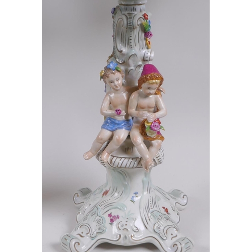 52 - A pair of continental porcelain four branch candelabra decorated with putti, 59cm high