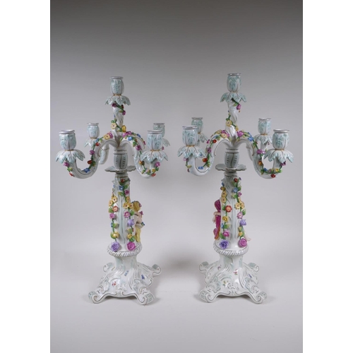 52 - A pair of continental porcelain four branch candelabra decorated with putti, 59cm high