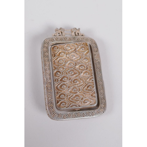 60 - A Chinese white metal and jade set pendant with revolving panel depicting buddha, 6cm x 4cm