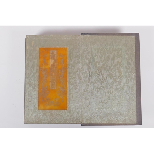 73 - A Chinese wood and silk bound book containing amber hardstone tablets with chased and gilt character... 