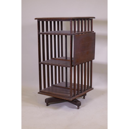 1158 - A Victorian oak revolving bookcase, three tiered with a ratcheted drop flap, raised on an iron base,... 