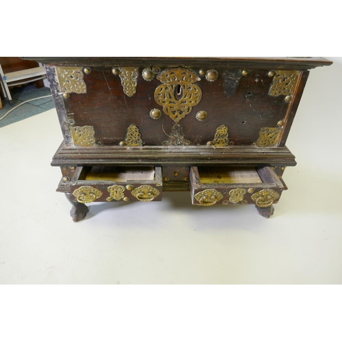 1001 - An C18th Dutch colonial teak chest with brass mounts, lift up top and two drawers, raised on claw fe... 