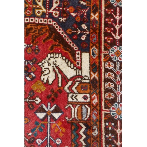 1016 - A hand woven red ground Persian carpet decorated with a geometric medallion, birds and camels, 158 x... 