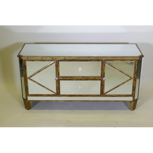 1029 - A giltwood side cabinet with inset bevelled mirrored glass, two cupboards flanking two drawers, with... 