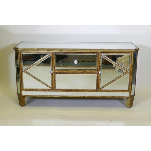 1029 - A giltwood side cabinet with inset bevelled mirrored glass, two cupboards flanking two drawers, with... 