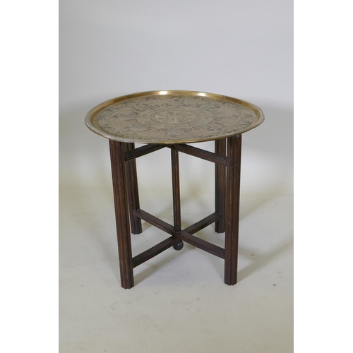 1035 - A Victorian brass top table with Japanese inspired decoration, on a folding wood base, 59 dia. x 55c... 