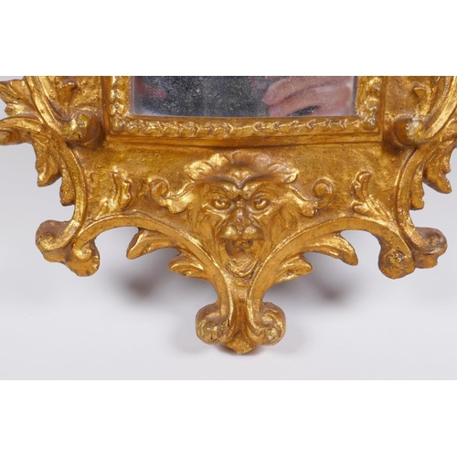 1046 - An Italian gilt wall mirror decorated with swags and masks, 28 x 65cm, losses