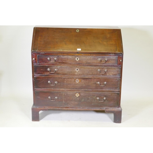 1069 - A Georgian mahogany bureau with four graduated drawers, the fall front fitted with pigeon holes and ... 