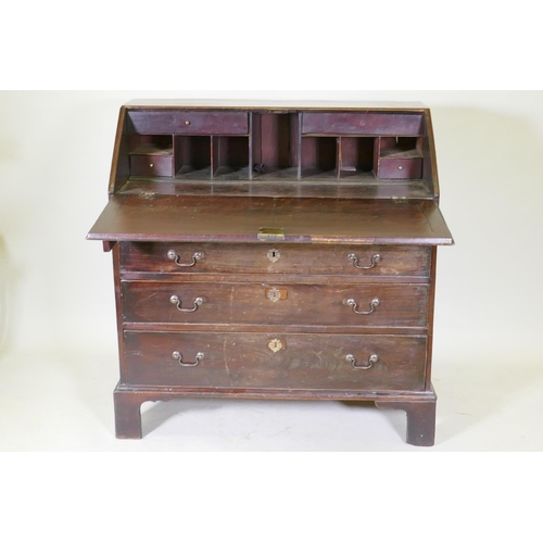 1069 - A Georgian mahogany bureau with four graduated drawers, the fall front fitted with pigeon holes and ... 