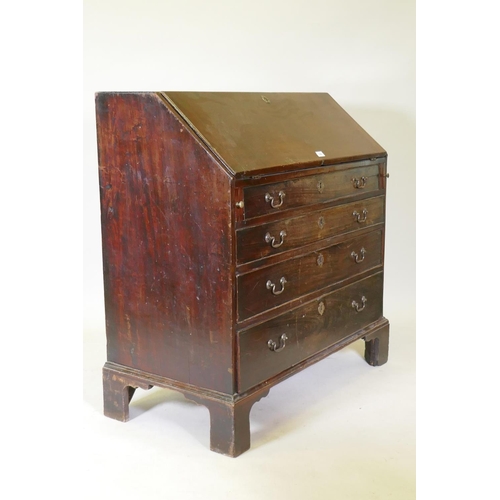 1069 - A Georgian mahogany bureau with four graduated drawers, the fall front fitted with pigeon holes and ... 