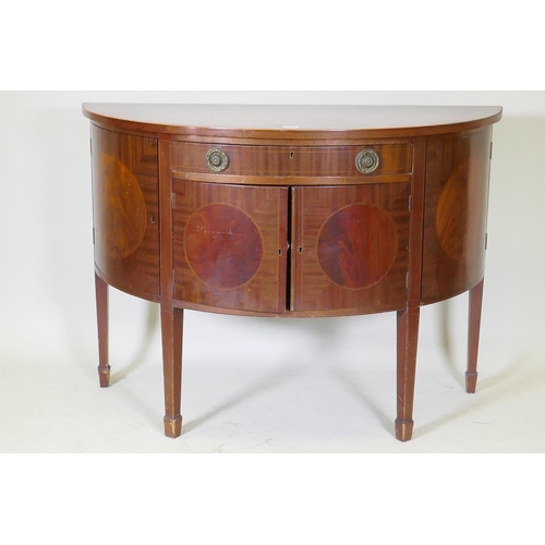 1072 - A C19th figured mahogany demi lune commode with two cupboards flanking a single drawer over two more... 