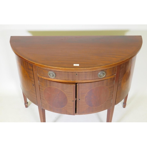 1072 - A C19th figured mahogany demi lune commode with two cupboards flanking a single drawer over two more... 