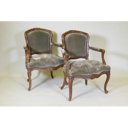 1077 - A pair of early C19th French walnut open arm chairs with carved crests and arms, serpentine front, r... 