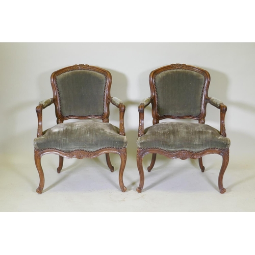 1077 - A pair of early C19th French walnut open arm chairs with carved crests and arms, serpentine front, r... 