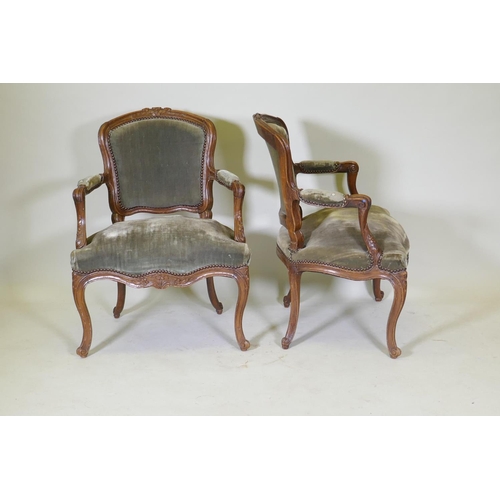 1077 - A pair of early C19th French walnut open arm chairs with carved crests and arms, serpentine front, r... 