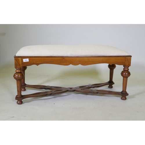 1083 - A walnut long stool with shaped frieze, raised on turned supports united by pierced shaped stretcher... 