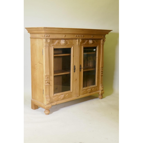 1100 - A C19th continental pine bookcase with two glazed door with applied fluted columns and lion mask dec... 