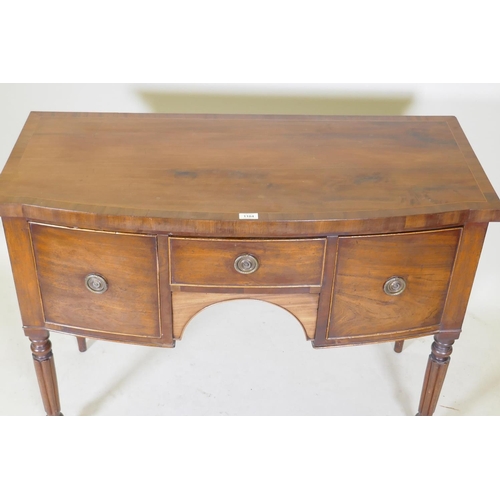 1104 - A Regency mahogany bow fronted kneehole sideboard with a cross banded top and three drawers, raised ... 