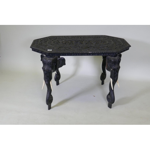 1124 - A C19th Ceylonese lacquered hardwood side table, the shaped top profusely carved with a procession a... 