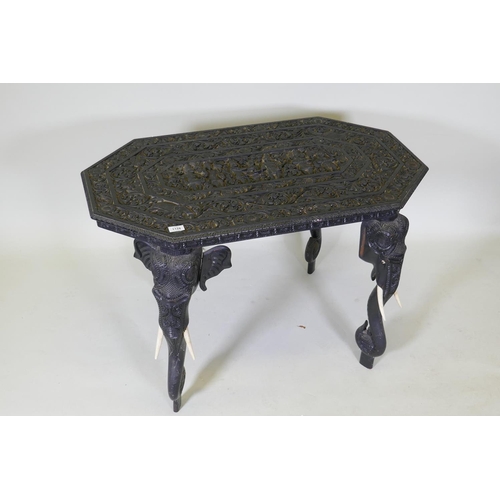 1124 - A C19th Ceylonese lacquered hardwood side table, the shaped top profusely carved with a procession a... 