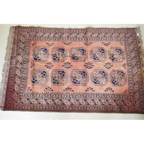 1130 - A vintage faded red hand woven wool Bokhara carpet with geometric designs, 130 x 210cm