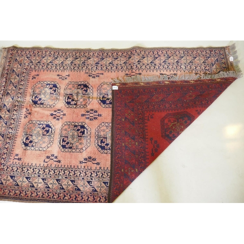 1130 - A vintage faded red hand woven wool Bokhara carpet with geometric designs, 130 x 210cm