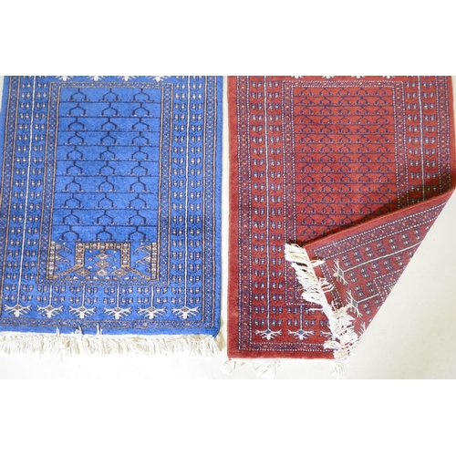 1134 - An oriental hand woven wool prayer rug with geometric designs on a red field and another in blue, 10... 