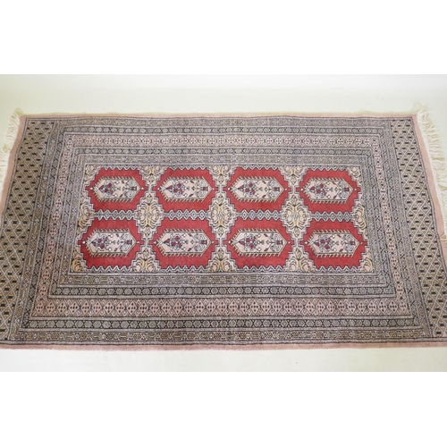 1137 - A hand woven wool Bokhara rug, medallion design on a pink ground, 94 x 150cm