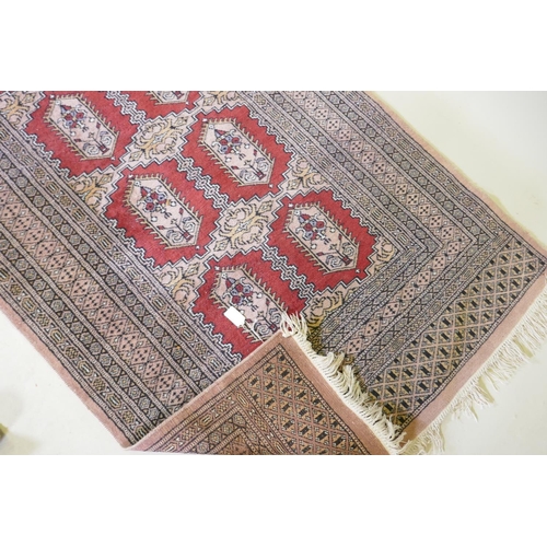 1137 - A hand woven wool Bokhara rug, medallion design on a pink ground, 94 x 150cm